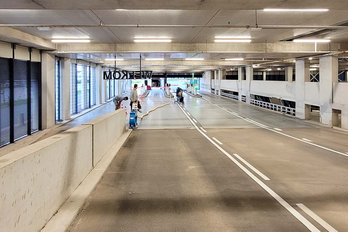 Werknemers reinigen en onderhouden het interieur van een parkeergarage met meerdere verdiepingen, waarbij ze er nauwgezet op toezien dat elke betonvloer vlekkeloos schoon is.