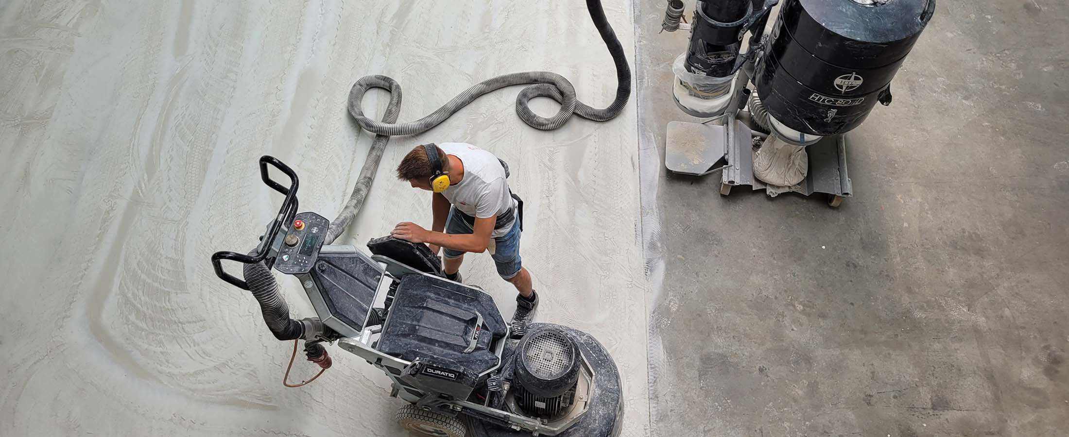 Een industriële vloerschuurmachine bewerkt een betonvloer om deze te vlakken