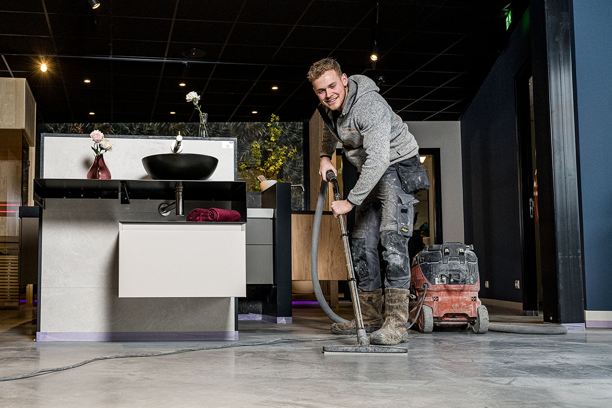 Een betonvloer met stof wordt schoongemaakt door een specialist van Hardeman vloerbewerking