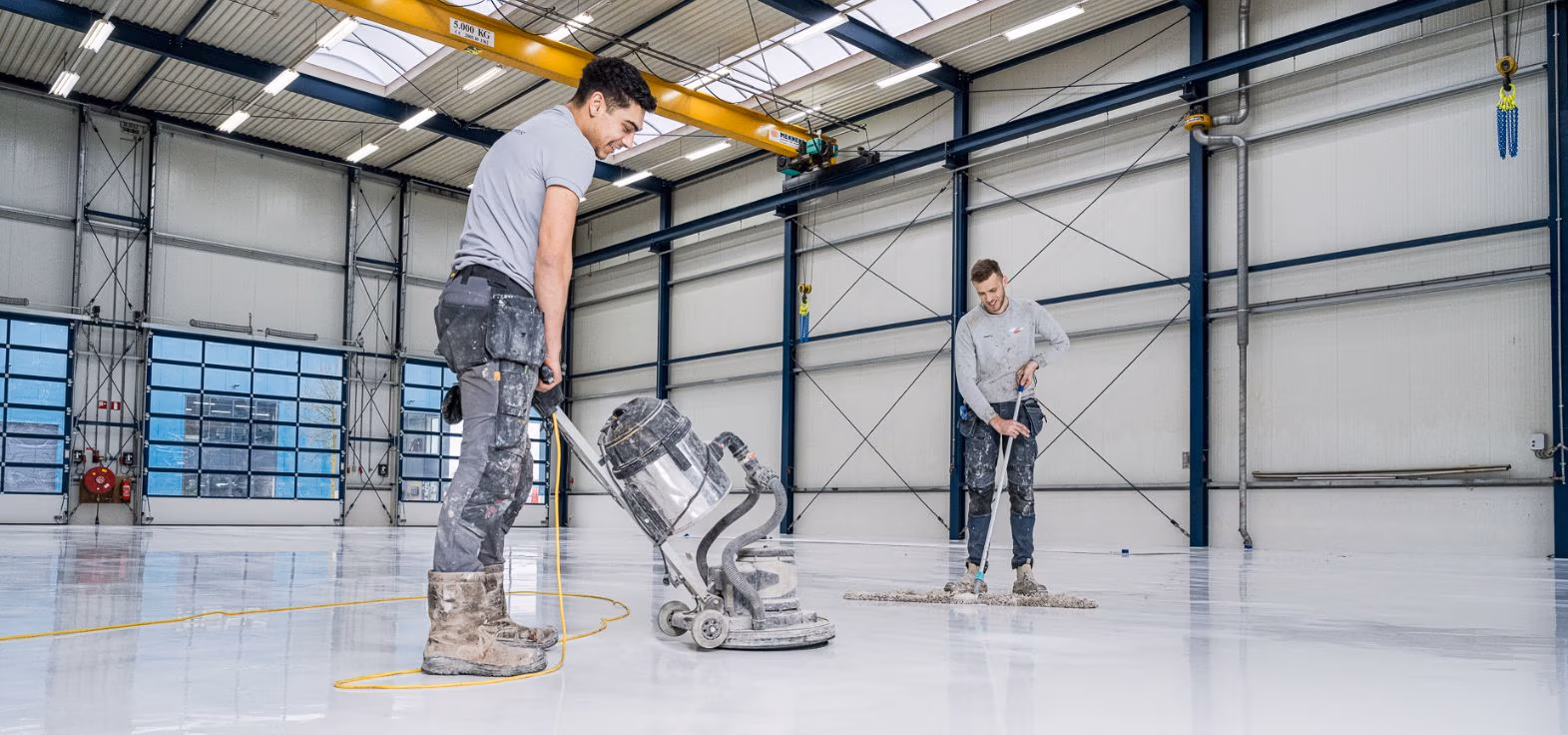 Twee vakmannen aan de slag met het coaten van een vloer