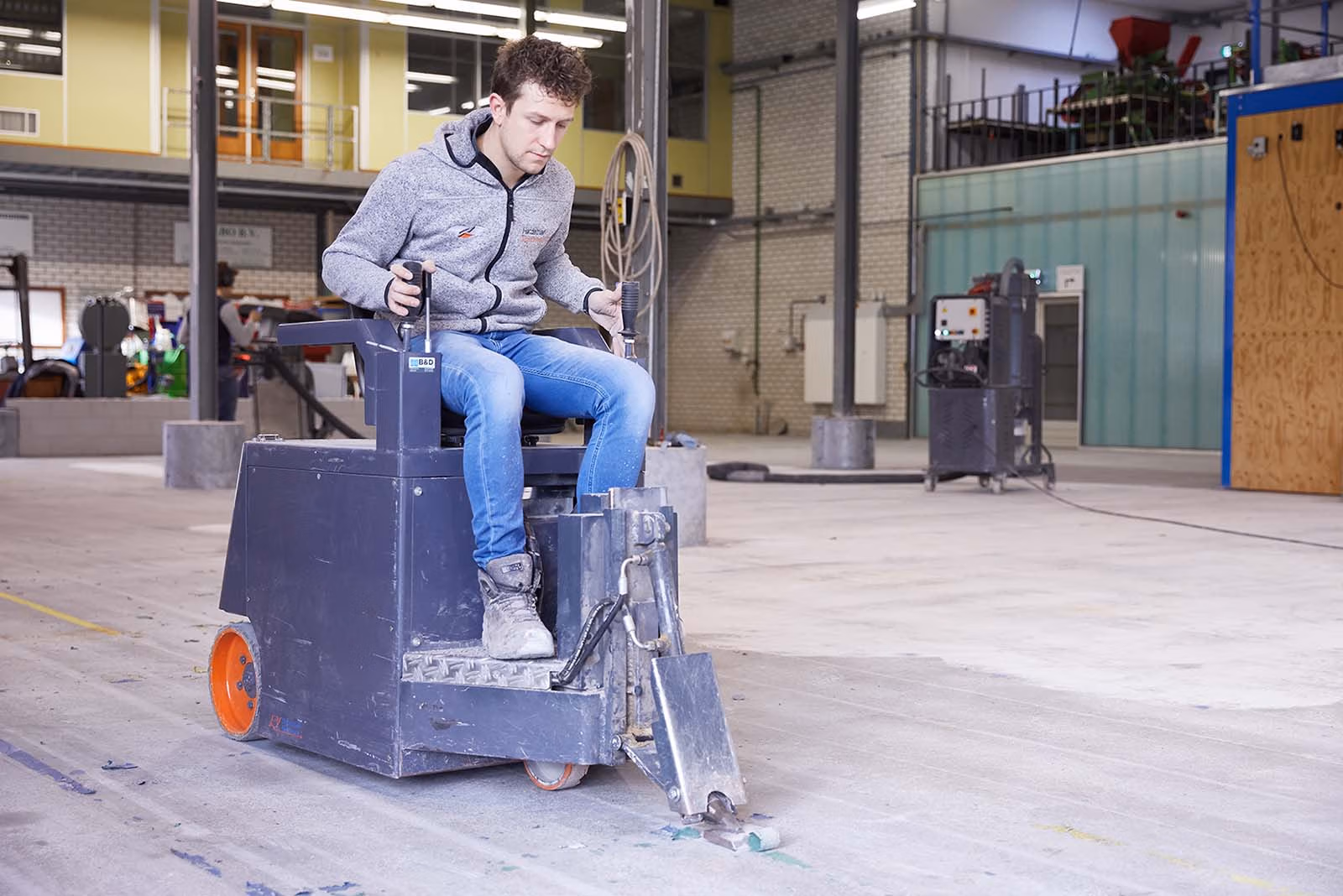 Vakman verwijdert vloercoating van beton met professionele apparatuur